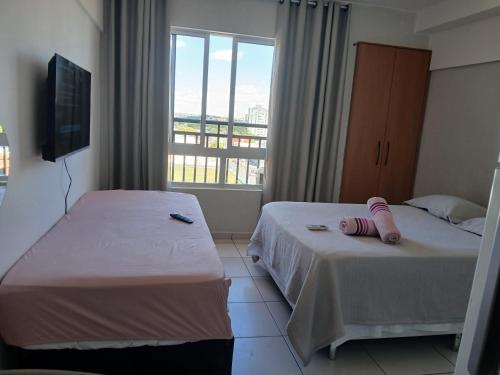 two beds in a hotel room with a window at Apartamento Estúdio in Teresina