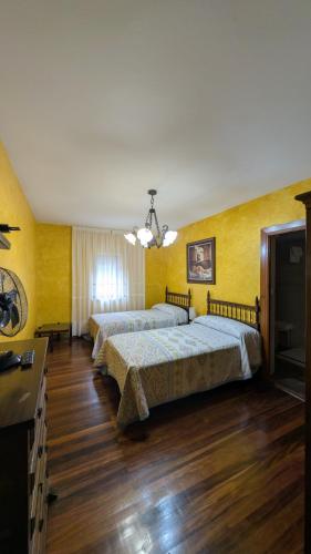 two beds in a room with yellow walls and wooden floors at Hostería Carmen in Santillana del Mar