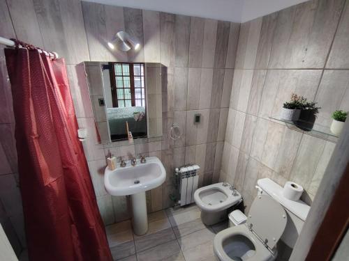 Un baño con lavabo, inodoro y espejo. en Casa Milo, en Mendoza
