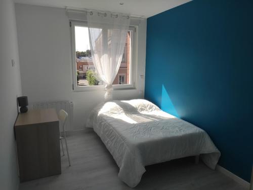 a bedroom with a bed with a blue wall and a window at Loftissime in Dunkerque