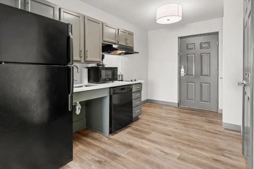 a kitchen with a black refrigerator and wooden floors at Candlewood Suites Hazleton by IHG in Hazleton