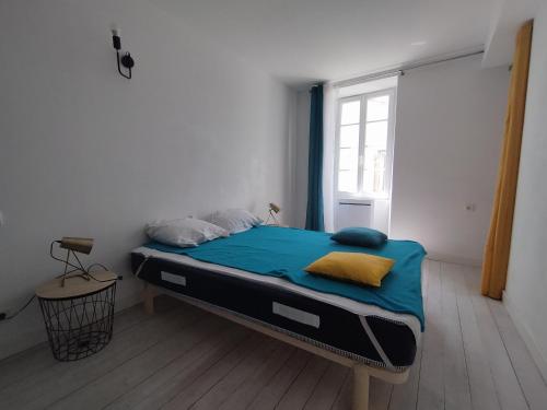 une chambre avec un lit avec des draps bleus et une fenêtre dans l'établissement La Jarne bis, à La Jarne