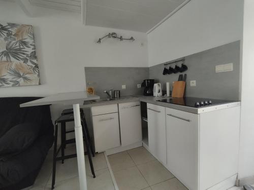 une petite cuisine avec des armoires blanches et une table dans l'établissement La Jarne bis, à La Jarne