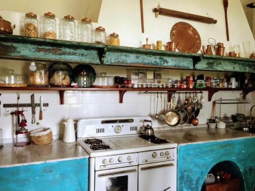 Una cocina con una estufa vieja y estantes con ollas y sartenes. en Estancia La Margarita, en Chascomús