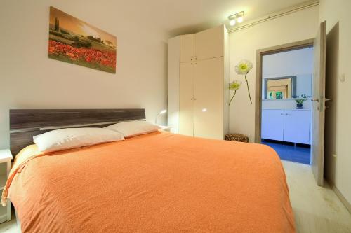 a bedroom with a bed with an orange blanket at Apartmani Kirinčić in Krk