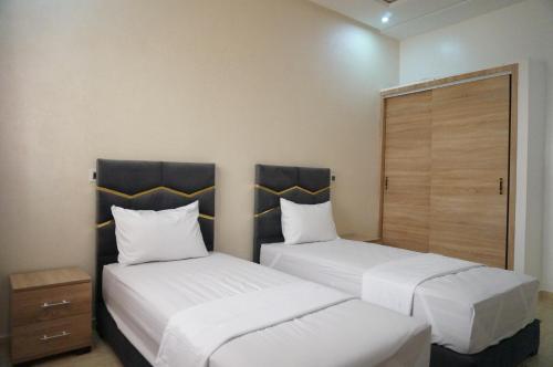 two beds in a small room with white sheets and pillows at 2 Voies Résidence in Dakhla