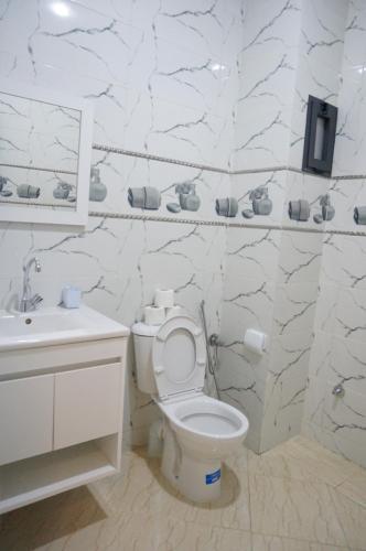 a white bathroom with a toilet and a sink at 2 Voies Résidence in Dakhla