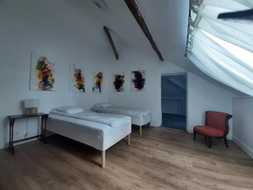 a room with two beds and a red chair at La Maison de Colette in Trie-Château