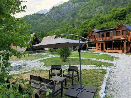 a table and chairs with an umbrella in front of a building at Thethi Villas in Theth
