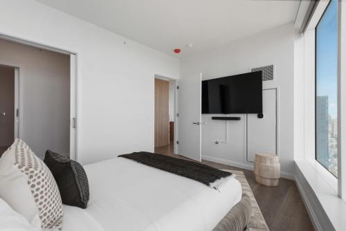 a white bedroom with a large bed and a flat screen tv at Lux Apts with Lake Views and Top Amenities in Chicago