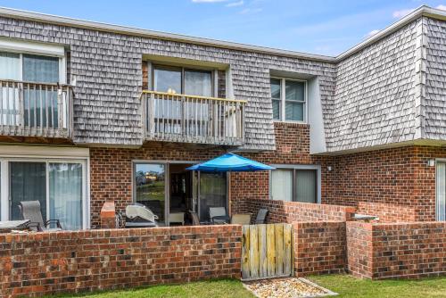 纳格斯黑德Delightful Dolphin的一座带有露台的砖房，露台上摆着一把蓝色的遮阳伞