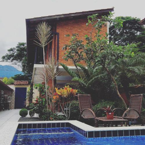 a house with a swimming pool in front of a house at Portal Suítes Casa do Lago in Paraty