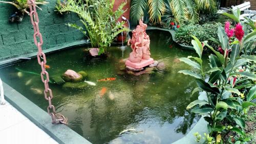 a koi pond with a statue in a garden at Portal Suítes Casa do Lago in Paraty