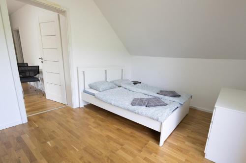 a white bedroom with a bed and a wooden floor at Ubytovanie Poloniny in Zboj