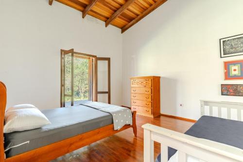 Un dormitorio con una cama y una cómoda y una ventana. en Quinta da Baronesa 2 - Sapucai Mirim, en Sapucaí-Mirim