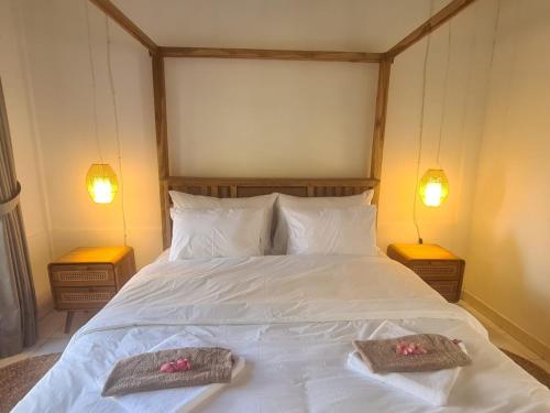 a bedroom with a white bed with two towels on it at Puring Bungalows Gili Air in Gili Air