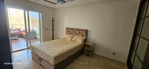a bedroom with a bed and a large window at Appartement tamaris in Sidi Rahal