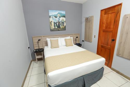 a bedroom with a bed and a wooden door at Hotel Los Altos Express "La Centroamerica" in Managua