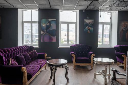 a living room with purple couches and tables and windows at Hedgehogs backpackers hostel in Rīga