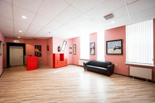 a waiting room with a black couch and pink walls at Hedgehogs backpackers hostel in Rīga