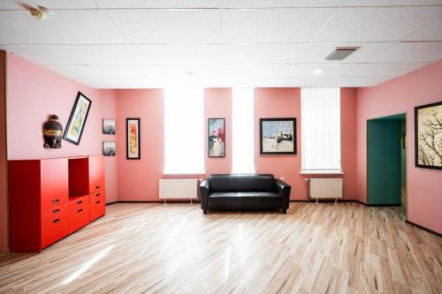 a room with a black couch in a room with pink walls at Hedgehogs backpackers hostel in Rīga