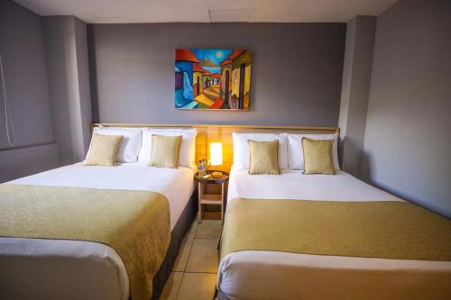 a hotel room with two beds and a painting on the wall at Hotel Los Altos Express "La Centroamerica" in Managua