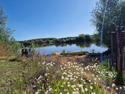 a body of water with a boat in the middle at GRETA Nowoczesny domek modułowy nad stawem in Jodłowiec
