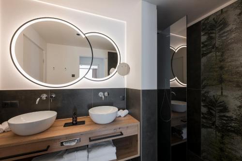 un bagno con due lavandini e uno specchio di Ramilia Family Apartments Restaurant & Pizzeria a Naturno