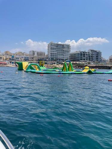 a row of inflatable water slides in the water at Spacious Bugibba Seafront Home 3BR Free Parking Free WiFi in St. Paul's Bay