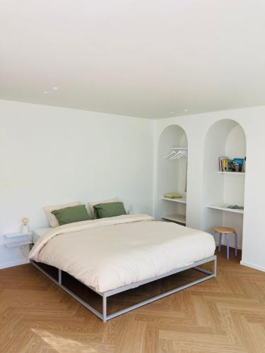 a white bedroom with a bed with white walls and wooden floors at Leaf Holiday Studio Kortrijk in Kortrijk