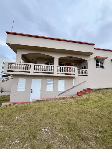 a white house with a balcony on top of a yard at Ocean View House in Quebradillas with Rooftop 