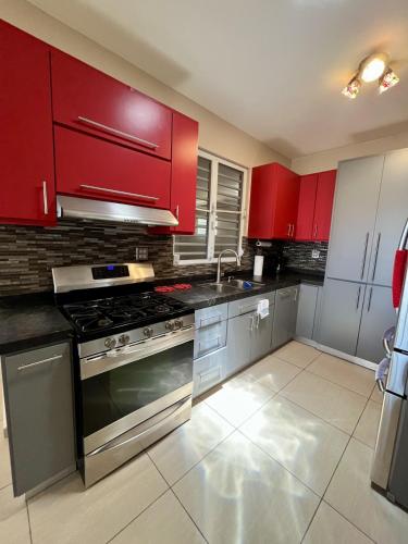 a kitchen with red cabinets and a stove top oven at Ocean View House in Quebradillas with Rooftop 