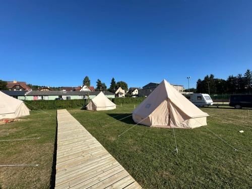 a group of tents in a field with a wooden walkway at Čerčanská Koupadla - glampingové stany in Benešov
