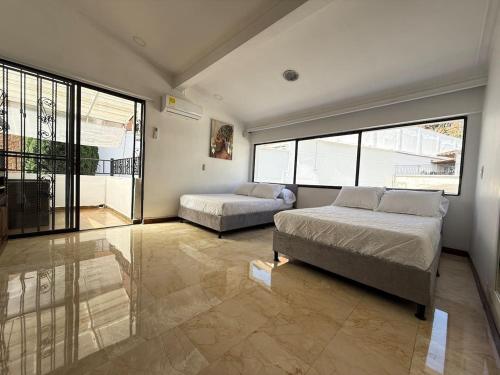 メデジンにある5BR Poblado 80s Mansion with Private Pool ACのベッドが2つと大きな窓がある寝室