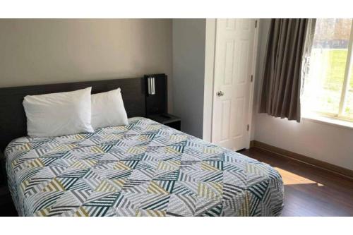a bedroom with a bed with a comforter and a window at Studio 6 Peoria IL in Peoria