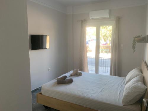 a bedroom with a large white bed with a window at Eva Apartment in Ermoupoli