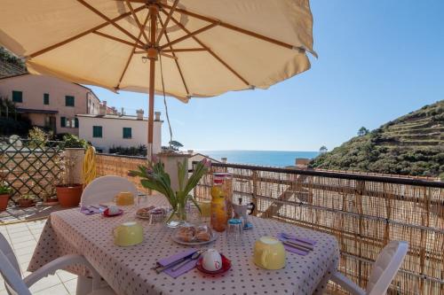 - une table avec un parasol sur un balcon donnant sur l'océan dans l'établissement Tracastello Home House with terrace e garage, à Riomaggiore