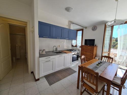 une cuisine avec des armoires bleues et une table et une salle à manger dans l'établissement Tracastello Home House with terrace e garage, à Riomaggiore