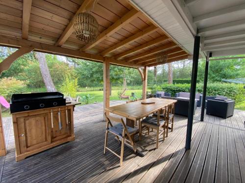 une terrasse en bois avec un grill et une table en bois dans l'établissement LANDES CHALET 8 personnes, à Lit-et-Mixe