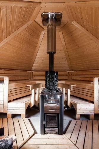 a stove in a wooden room with a ceiling at Udden in Herräng