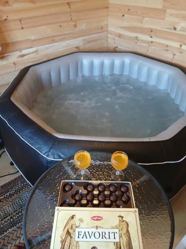 a hot tub with a table and two glasses on it at Pensiune Colina Farm in Găgeni