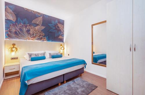 a bedroom with a bed with blue sheets and a mirror at Mare & Monti in Mlini
