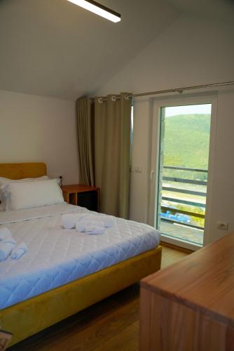 a bedroom with a bed and a sliding glass door at Bujtina Adora in Ara të Lumit