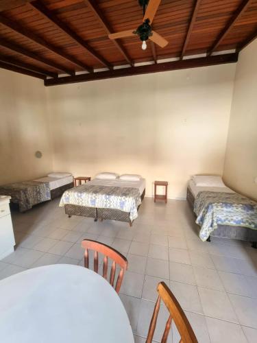 a room with three beds and a table and chairs at Hotel Fênix in Florianópolis