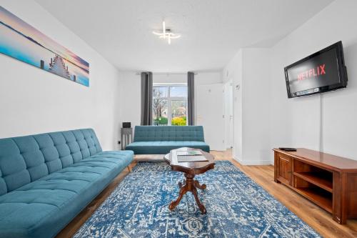 a living room with blue couches and a tv at 3BDR Gated parking near city centre in Manchester