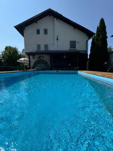 a large blue swimming pool in front of a house at Къща за гости Заркови in Gaber