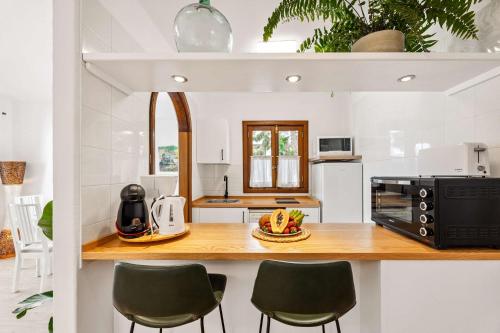 een keuken met een aanrecht met een magnetron en stoelen bij El Nido Seafront Hideaway by Bayside in Playa Honda