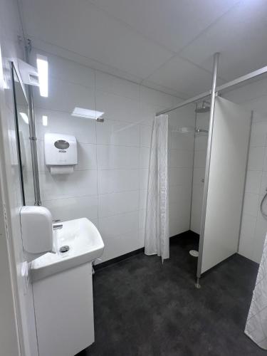 a white bathroom with a sink and a shower at Rentalux Hostel - Modern Comfort, Single Rooms in Timrå