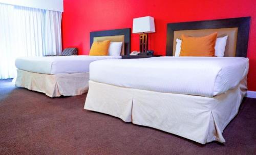 two beds in a hotel room with red walls at Studio 6 Anaheim Hills CA in Anaheim