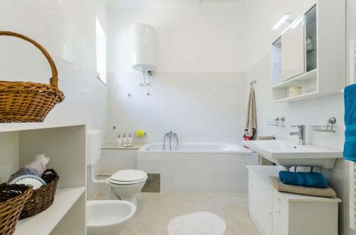 a white bathroom with a toilet and a sink and a tub at Holiday home in Drivenik 39517 in Drivenik